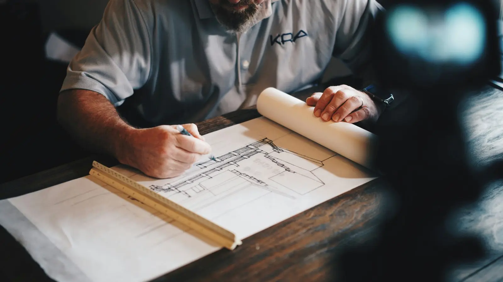 Construction business owner reviewing blueprints while planning project costs and job profitability.